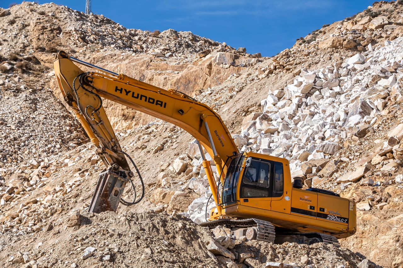 Mastering the First Impression: Your intriguing post title goes here Yellow Hyundai excavator operating in a rocky quarry under a clear blue sky. Perfect for industrial themes.