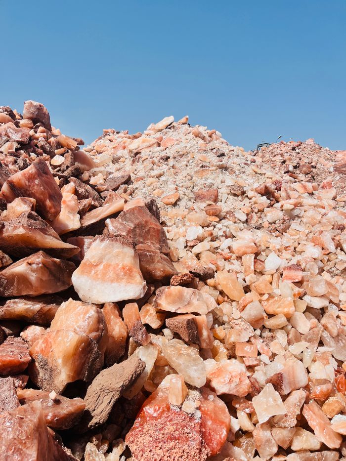 services-bg Close-up of pink and orange Himalayan salt rock piles with a clear blue sky backdrop.