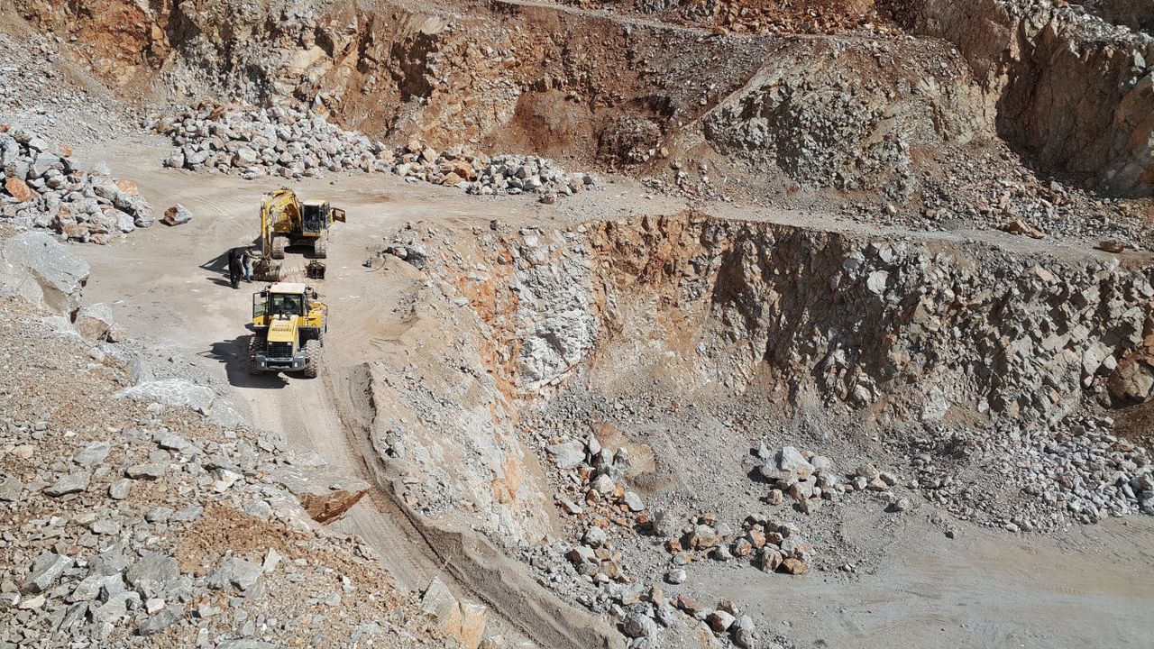 An open-pit mining site featuring excavators and loaders amid rocky terrain.